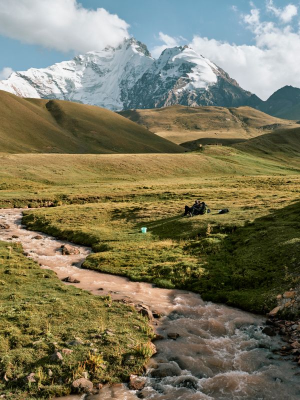 A stream in the Kyzylsu catchment area (river basin) with the mountain glaciers and snow that supply it in the background.
